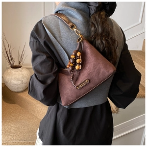 Détail du sac hobo en daim marron foncé avec pendentif de perles en bois rétro élégant