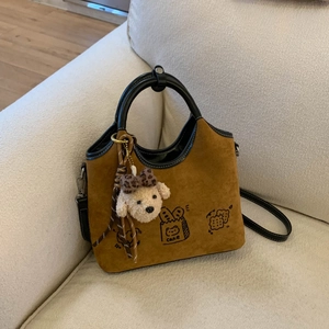 Détail d'un sac à main en daim caramel avec motifs de dessins animés et breloque