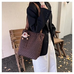 Dettaglio della borsa tote trapuntata marrone scuro con ciondolo a forma di agnello bianco