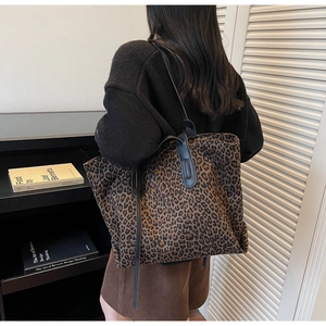 Sac fourre-tout chic léopard avec lanières en cuir noir porté par un mannequin