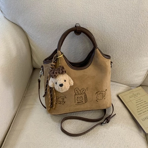 Détail du sac vintage en daim marron avec imprimé pain mignon et breloque chien peluche