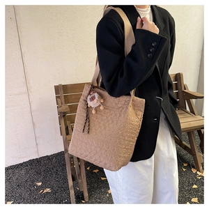 Dettaglio della borsa tote trapuntata kaki con tracolla larga e ciondolo a forma di orso