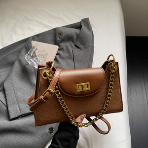 Detailaufnahme der braunen Wildledertasche mit Goldkette und quadratischem Drehverschluss