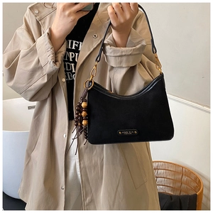 Detail of black suede hobo bag with gold hardware and brown wooden bead tassel charm