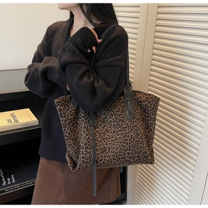 Sac fourre-tout léopard porté avec un tricot noir et une jupe marron dans un intérieur