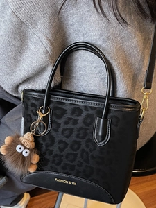 Chic black leopard jacquard handbag with plush monster charm and leather trim