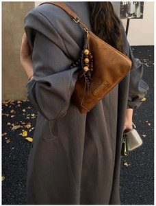 Sac à bandoulière en daim marron avec perles en bois rétro sur une tenue d'automne
