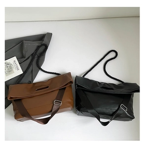 Detail view of brown and black envelope flap bags with thick twisted rope handles