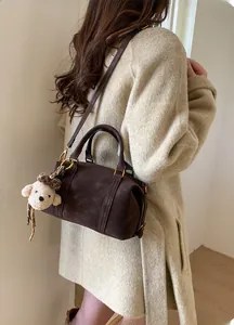 Detail of dark brown Boston bag with ZSKERT embossed logo and plush bear charm