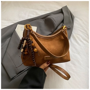 Détail d'un sac hobo en daim marron avec gland en perles de bois et anneaux dorés élégants