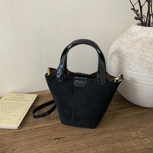 Detail view of black vintage bucket bag on wooden surface with retro aesthetic setup