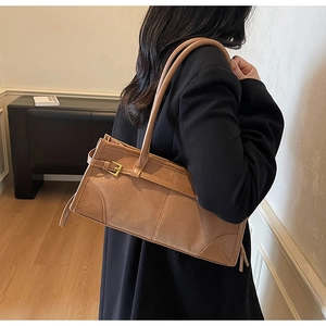 Detail view of brown patchwork underarm bag with suede texture and metal buckle accents
