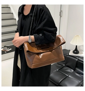 Detail of soft brown leather tote bag with unique woven strap worn by a model in interior