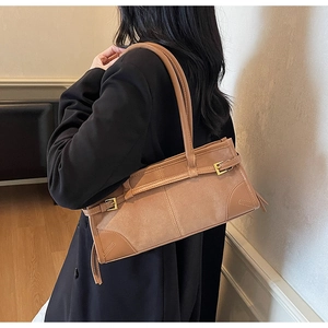 Brown retro baguette bag shown on shoulder with matte leather finish and metal buckles