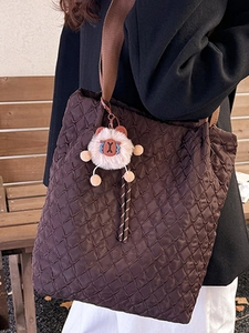 Borsa tote trapuntata marrone con tracolla e ciondolo a forma di orso in ambientazione esterna