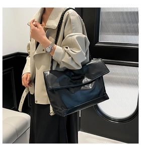 Detail of minimalist black tote bag featuring a distinctive thick woven rope shoulder strap