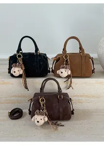 Detail of Boston handbags in black and brown with suede texture and dog charm