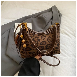 Sac hobo léopard avec garniture en cuir et gland sur un fond de couleur neutre