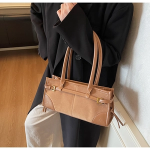 Close-up of retro baguette bag featuring brown suede texture and golden metal buckle