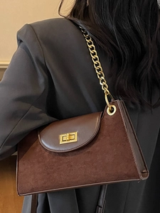 Braune minimalistische Patchwork-Achseltasche mit Goldkette auf grauem Blazer