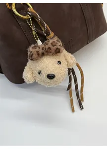 Close-up of plush puppy bag charm with leopard bow on dark brown handbag accessory