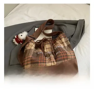 Detailed macro view of checkered wool tote bag with suede base and bear keychain