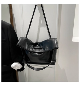Detail of black tote bag featuring a thick twisted rope strap and soft folded opening
