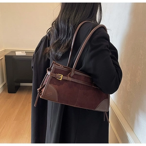Detail of vintage brown suede baguette bag with leather straps and gold buckle
