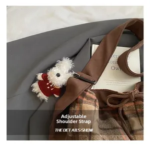 Close-up of brown plaid tote bag with bow detail and cute plush rabbit charm