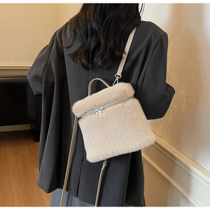 Detail der cremefarbenen Plüschtasche mit Kunstpelz-Textur und Lederriemen am Modell