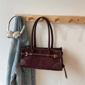 Close-up of retro reddish-brown baguette bag with suede panels and gold hardware detail
