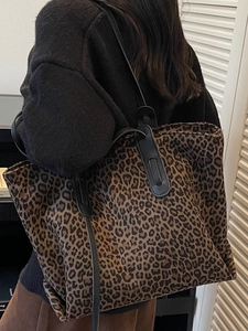 Grand sac cabas tendance à imprimé léopard avec anses noires porté à l'épaule par un mannequin