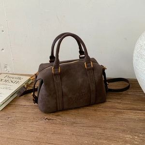 Close-up of retro dark brown matte leather boston bag with golden hardware details