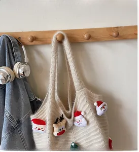 Detail of a beige knitted tote bag with soft straps and Christmas themed plush decorations