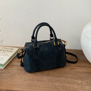 Detail view of navy blue frosted leather Boston bag with metal hardware on wood surface