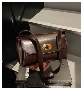 Détail d'un sac à main en similicuir marron brillant avec élégant fermoir doré ovale