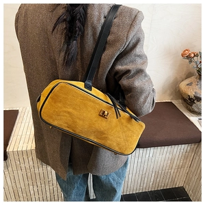 Detail of yellow suede baguette bag with vintage metal twist lock and black leather strap