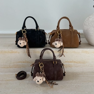 Three boston bags in black and brown on marble steps with plush bear pendants