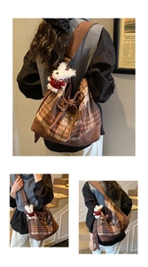 Detail view of large brown plaid tote bag with wide strap and plush bunny pendant