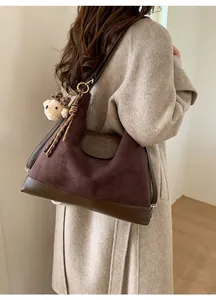 Close-up of a large vintage brown tote bag featuring suede texture and cute bear charm