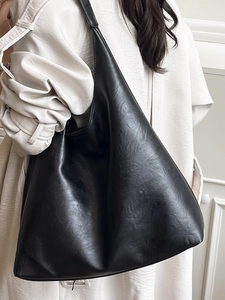 Vintage large black leather tote bag with crinkled texture worn by a model