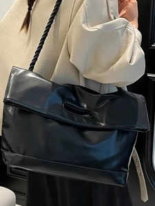 Vintage large black leather tote bag with thick woven shoulder strap and oval handle cutout