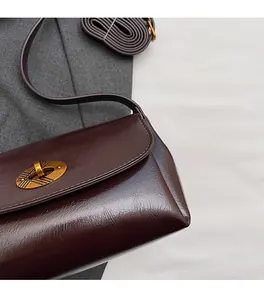 Vue détaillée de la texture du cuir bordeaux foncé et du fermoir rotatif ovale doré