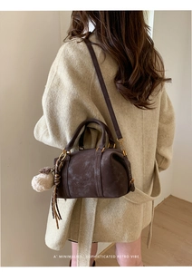 Detail of vintage brown Boston bag with shoulder strap and plush charm on a model
