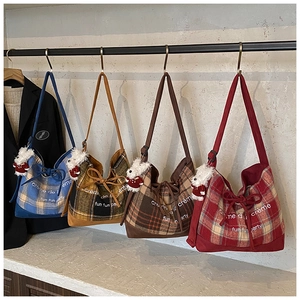 Detail view of four colorful vintage plaid tote bags with plush bear charms