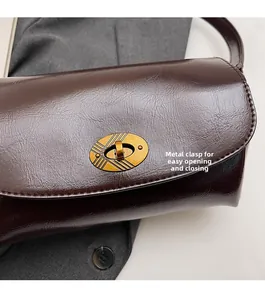 Gros plan du fermoir pivotant doré sur le sac à main en cuir marron foncé