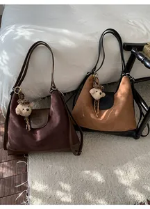 Close-up of vintage suede tote bags with elephant embossing and plush bear charm detail