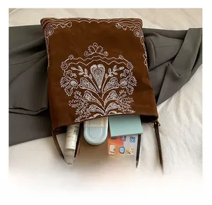 Detail view of large brown suede tote bag with white embroidery showing spacious interior