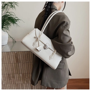 Chic beige leather Boston bag with silver lock detail shown on model in minimalist setting