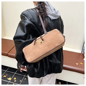 Detail of a khaki suede baguette bag with leather strap and gold protective metal feet